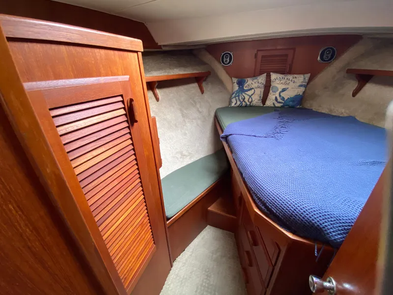 Slide: The Image of 1984 Tollycraft 34 Convertible Sedan cabin with wooden interior and cozy bedding. - 13