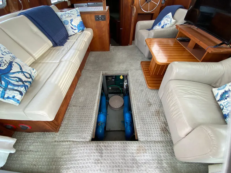 Slide: The Image of 1984 Tollycraft 34 Convertible Sedan interior with open engine hatch, beige seating, and nautical decor. - 28