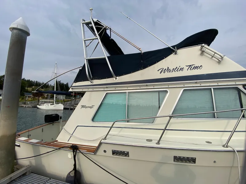 Slide: The Image of 1984 Tollycraft 34 Convertible Sedan docked, named "Wastin Time," with blue cover. - 35