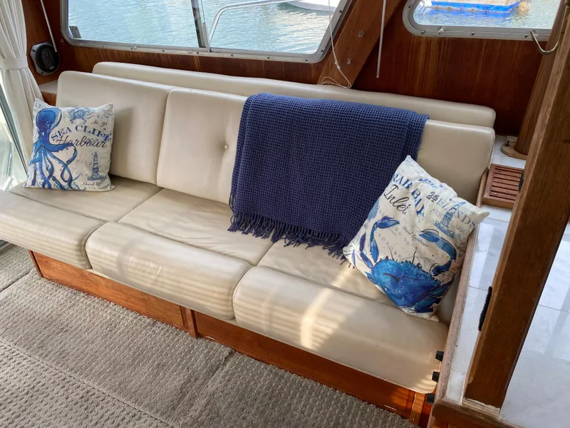 Slide: The Image of 1984 Tollycraft 34 Convertible Sedan interior with nautical-themed pillows and a blue throw blanket. - 4