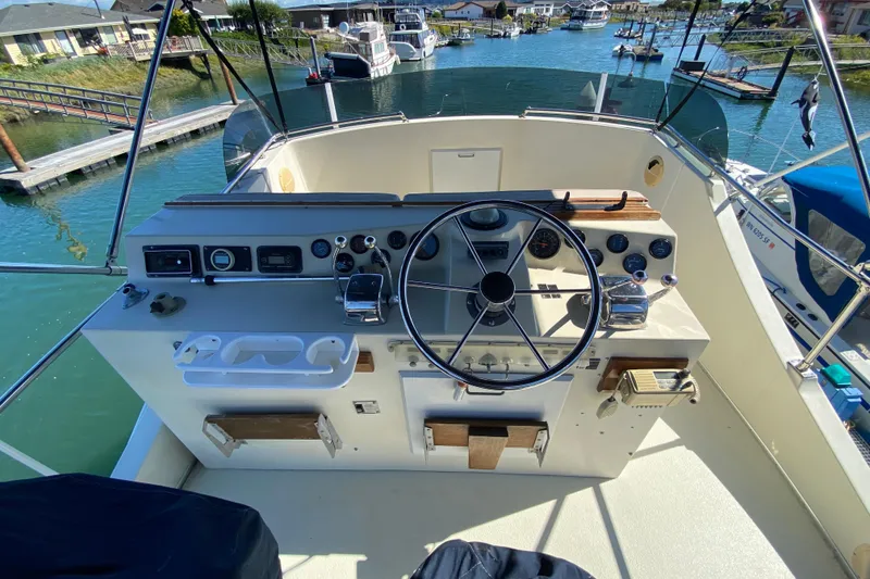 Slide: The Image of 1984 Tollycraft 34 Convertible Sedan helm with steering wheel and control panel, docked in marina. - 43