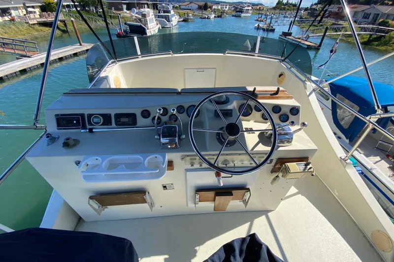 Slide: The Image of 1984 Tollycraft 34 Convertible Sedan helm with steering wheel and control panel, docked in marina. - 49