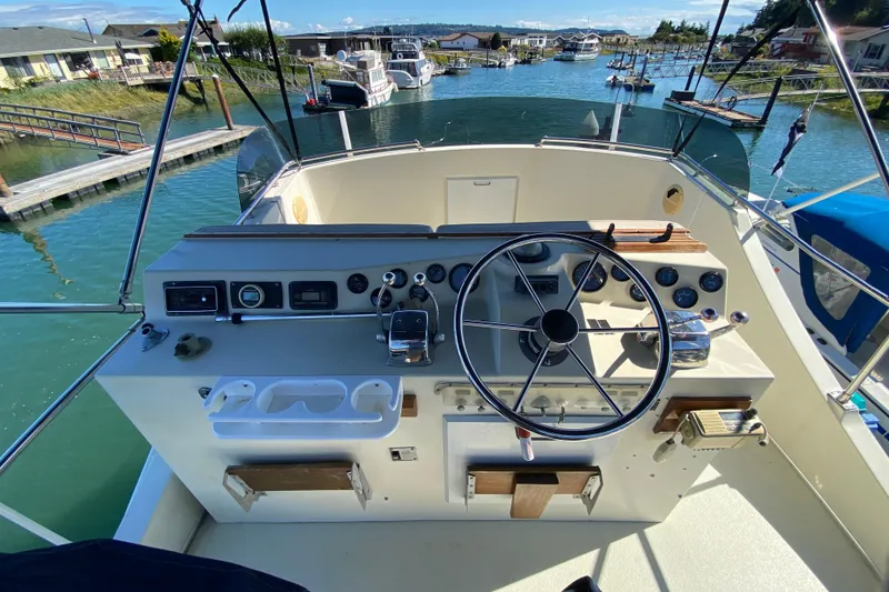 Slide: The Image of 1984 Tollycraft 34 Convertible Sedan helm with steering wheel and control panel, docked in marina. - 51