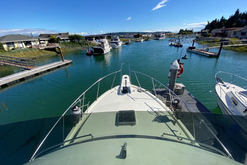 Slide: The Image of 1984 Tollycraft 34 Convertible Sedan docked in a scenic marina under clear blue skies. - 52