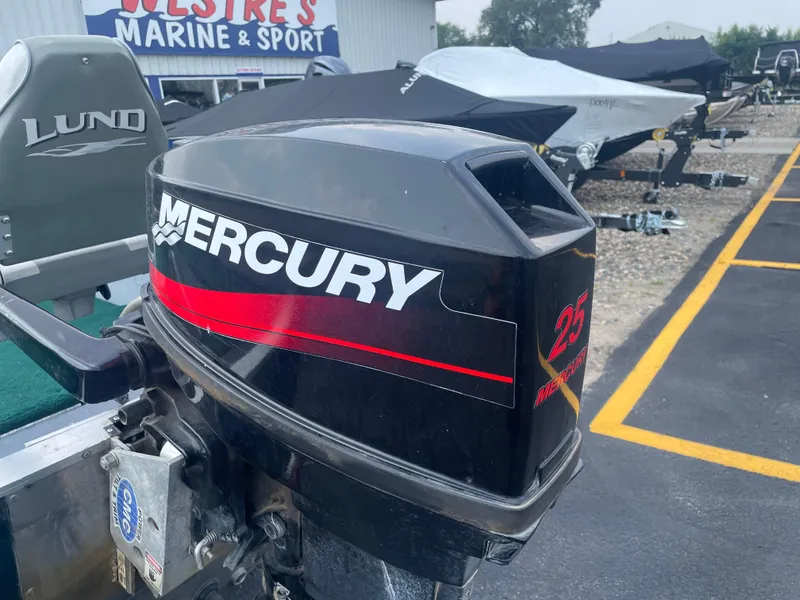 Slide: The Image of 2003 Lund 1650-V Rebel Tiller with Mercury 25 outboard motor at marine dealership. - 14