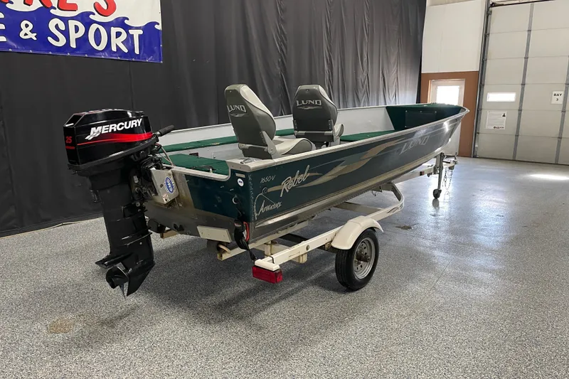 Slide: The Image of 2003 Lund 1650-V Rebel Tiller boat with Mercury engine on trailer in showroom. - 2