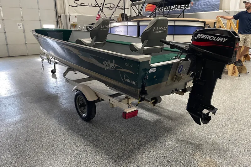 Slide: The Image of 2003 Lund 1650-V Rebel Tiller boat with Mercury outboard motor in a showroom. - 3