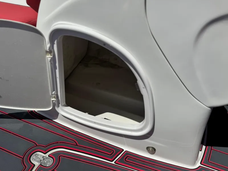 Slide: The Image of Open storage compartment on 2018 Tracker TAHOE 215 XI boat with red and black flooring. - 32
