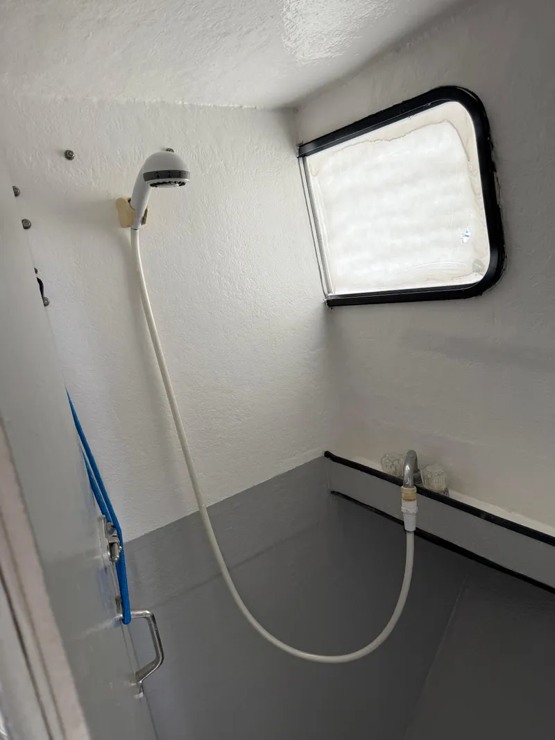 Slide: The Image of Compact shower area inside a 2004 Jefferson Lafitte boat, featuring a window and handheld showerhead. - 11