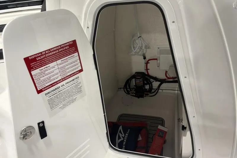 Slide: The Image of Open storage compartment in 2026 Tidewater 232 CC Adventure boat, showing safety equipment and wiring. - 12