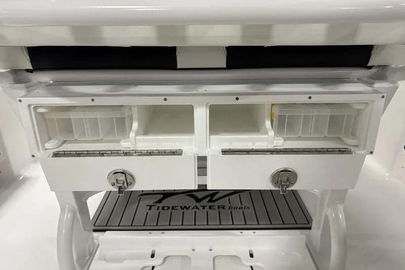 Slide: The Image of 2026 Tidewater 232 CC Adventure boat storage compartments with secure locks and branded mat. - 24