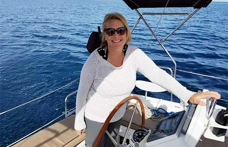 Slide: The Image of Woman smiling on a 2007 Beneteau 343 sailboat, steering on open water. - 6