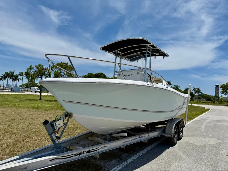 Slide: The Image of 2016 Key Largo 2100 WI CC boat on trailer, parked outdoors under blue sky. - 1