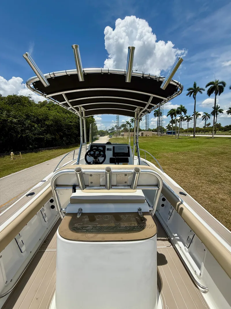 Slide: The Image of 2016 Key Largo 2100 WI CC boat with T-top, steering console, and rod holders under a blue sky. - 24