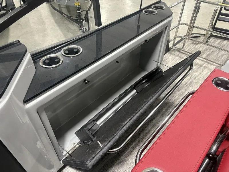 Slide: The Image of Open storage compartment on 2025 Godfrey AquaPatio 235 DFLC boat, featuring cup holders and sleek design. - 30