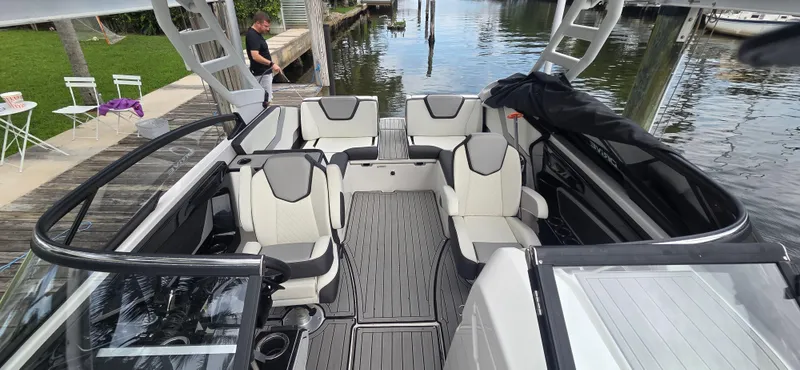 Slide: The Image of 2023 Yamaha Boats 252SD interior with sleek seating and modern design at a dock. - 21