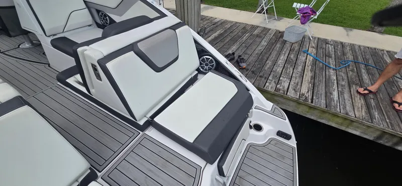 Slide: The Image of 2023 Yamaha Boats 252SD interior with sleek seating and modern design on a wooden dock. - 29