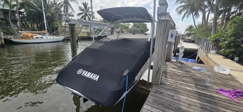 Slide: The Image of 2023 Yamaha Boats 252SD covered and docked by a scenic waterfront with palm trees. - 3
