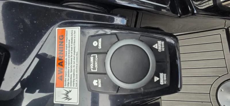 Slide: The Image of Control panel of 2023 Yamaha Boats 252SD with warning label and cruise control buttons. - 35