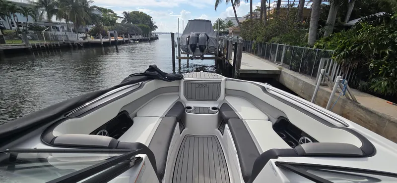 Slide: The Image of 2023 Yamaha Boats 252SD interior, docked in a scenic waterfront setting with lush greenery. - 4