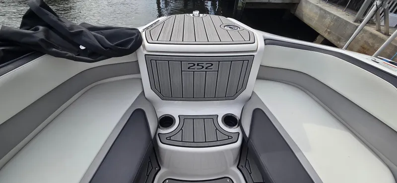 Slide: The Image of 2023 Yamaha Boats 252SD interior with sleek seating and storage, docked by the water. - 7