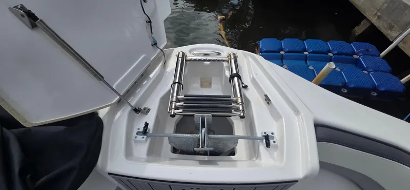 Slide: The Image of 2023 Yamaha Boats 252SD anchor compartment with ladder, dockside view. - 8