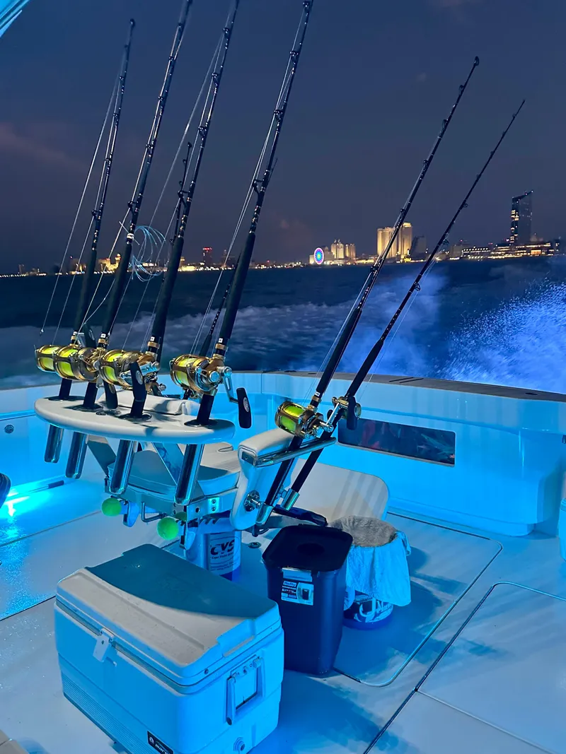 Slide: The Image of Fishing rods on a 2009 Viking 64 Convertible yacht at night, city skyline in background. - 48