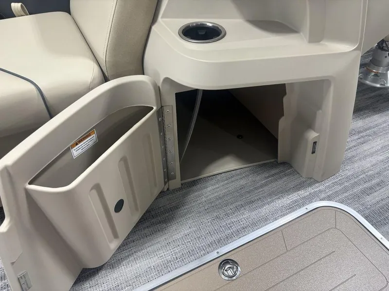 Slide: The Image of Open storage compartment on 2025 Godfrey Sweetwater 2286 SFLC boat, featuring beige interior and cup holder. - 17