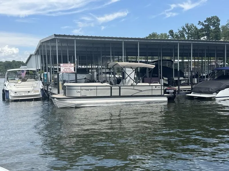 The Image of 2019 Manitou 250 SHP pontoon boat docked at marina with other boats. - 1