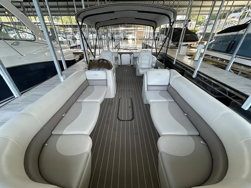 Slide: The Image of 2019 Manitou 250 SHP pontoon boat with spacious seating and canopy in a marina. - 10