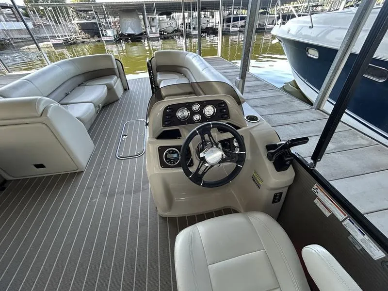 Slide: The Image of 2019 Manitou 250 SHP pontoon boat interior with steering console and seating. - 5