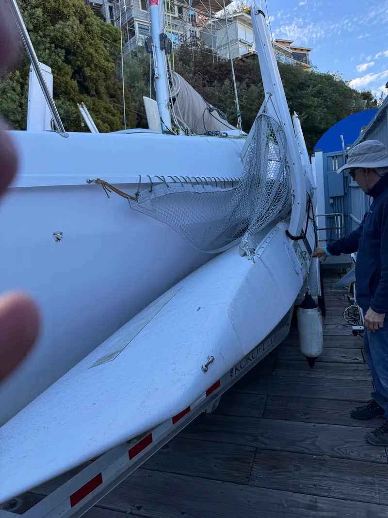 Slide: The Image of 2018 Corsair 760 Sport sailboat on trailer, docked with a person nearby. - 15