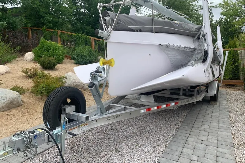 Slide: The Image of 2018 Corsair 760 Dash sailboat on trailer, parked on gravel driveway. - 2