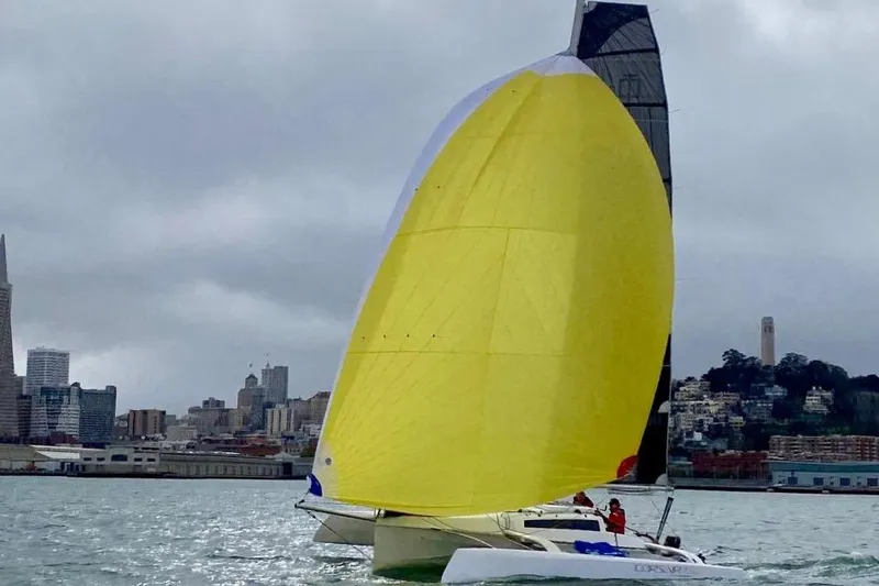 Slide: The Image of Sailboat Corsair 760 Dash 2018 with yellow sail on a cloudy day near city skyline. - 5