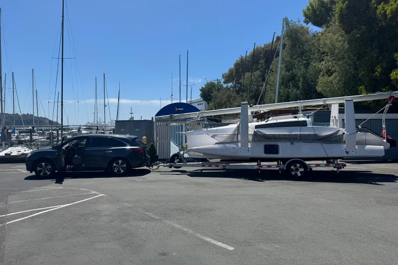 Slide: The Image of SUV towing a 2018 Corsair 760 sailboat on a trailer at a marina parking lot. - 19