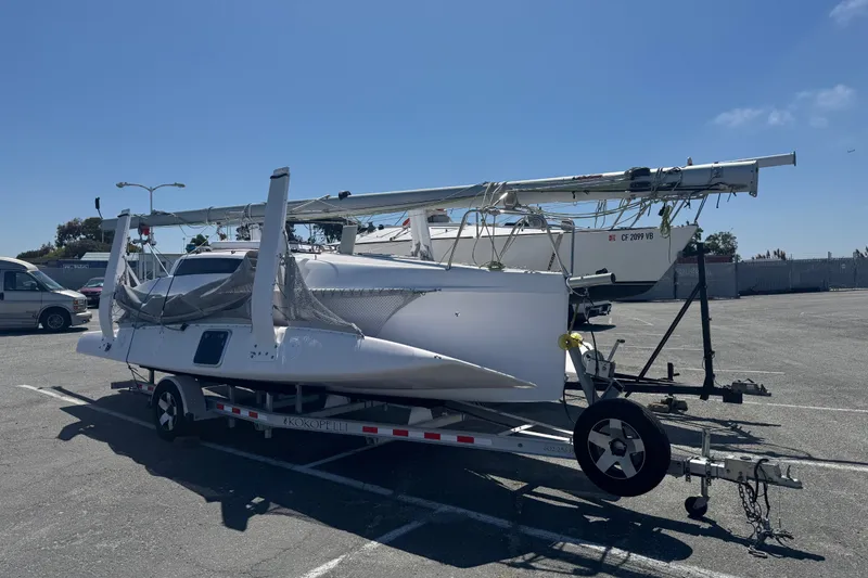 Slide: The Image of 2018 Corsair 760 sailboat on trailer in parking lot under clear blue sky. - 18