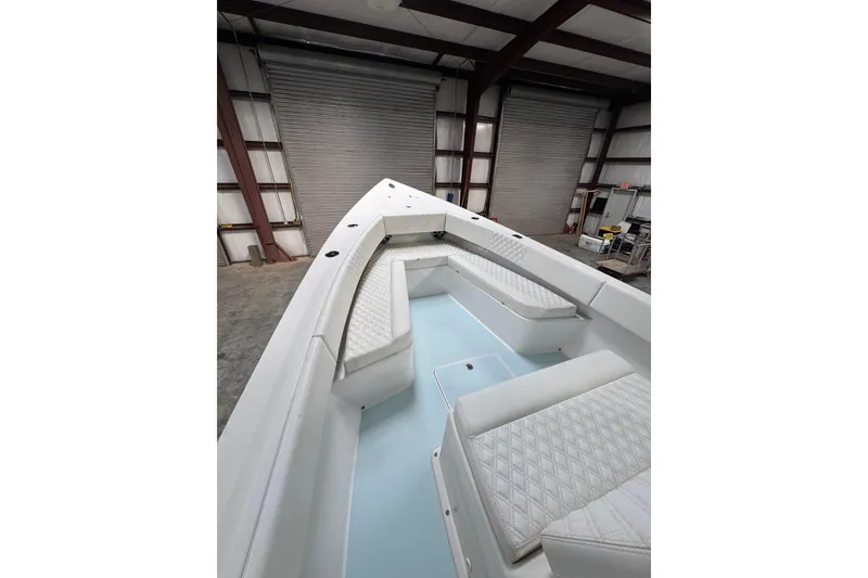 Slide: The Image of 2023 Calypso Center Console boat interior with white seating in a warehouse. - 22