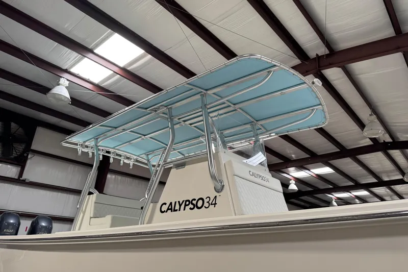Slide: The Image of 2023 Calypso Center Console boat with blue canopy in a warehouse setting. - 36