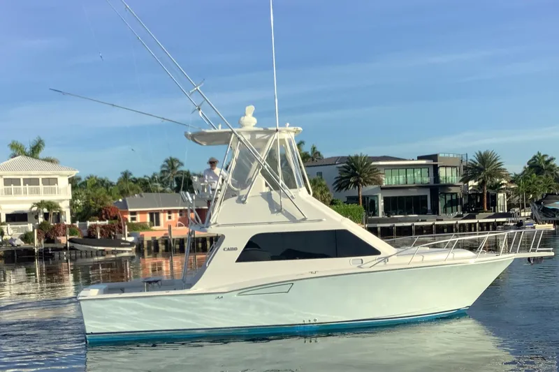 The Image of 2006 Cabo 35 Flybridge Sportfisher on calm water near luxury waterfront homes. - 0