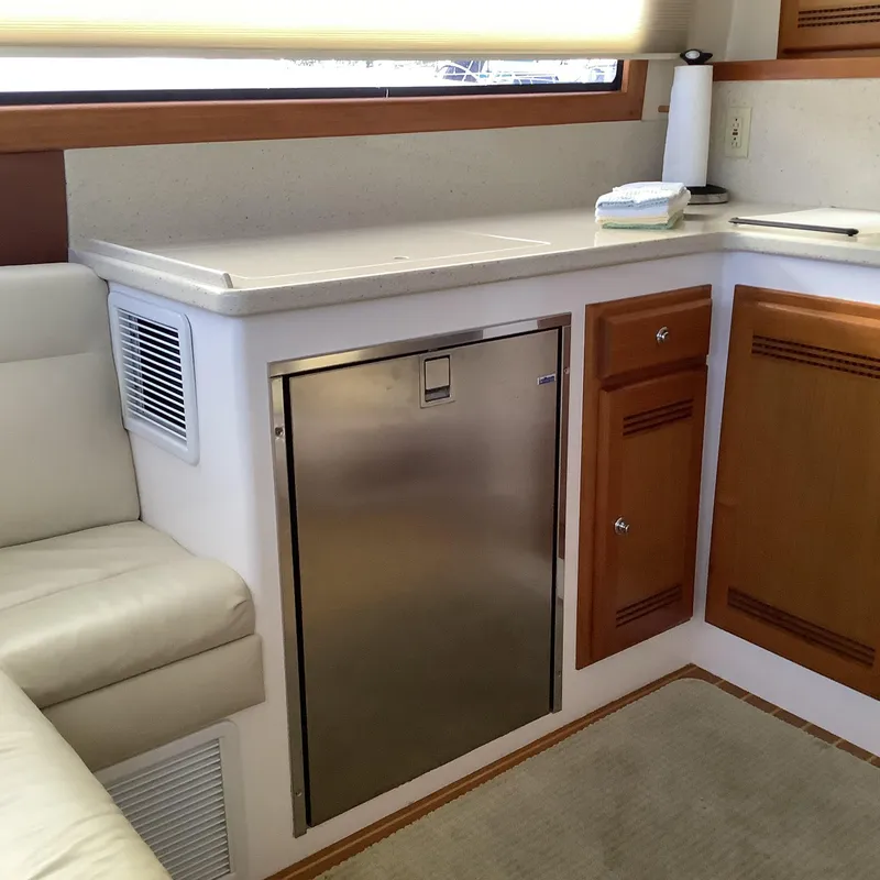 Slide: The Image of 2006 Cabo 35 Flybridge Sportfisher interior with stainless steel fridge and wooden cabinetry. - 17