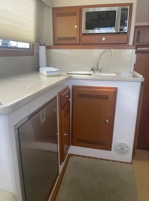 Slide: The Image of 2006 Cabo 35 Flybridge Sportfisher kitchen with microwave, sink, and wooden cabinets. - 18