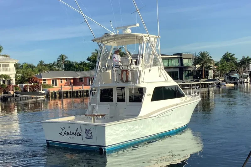 Slide: The Image of 2006 Cabo 35 Flybridge Sportfisher boat on calm water near waterfront homes. - 2