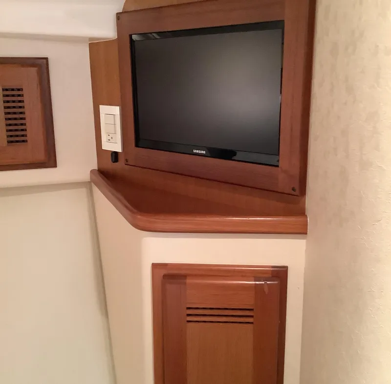 Slide: The Image of 2006 Cabo 35 Flybridge Sportfisher interior with wall-mounted TV and wooden cabinetry. - 29