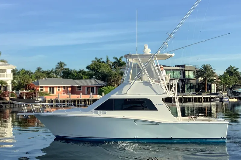 Slide: The Image of 2006 Cabo 35 Flybridge Sportfisher boat on calm water near waterfront homes. - 3