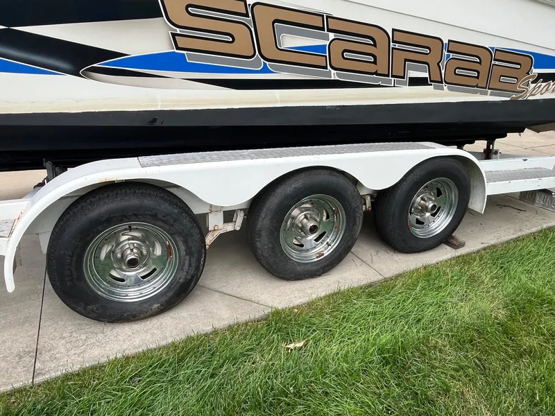 Slide: The Image of Trailer with Wellcraft 302 SCARAB SPORT boat, showcasing triple axle wheels. - 24
