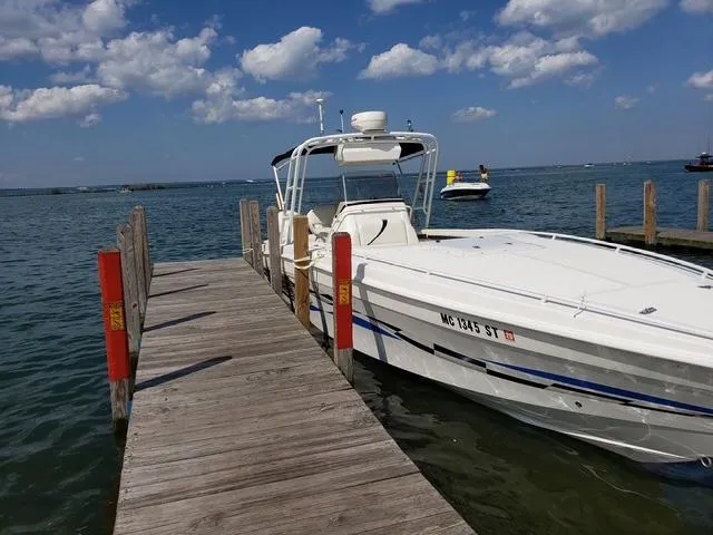 Slide: The Image of 2000 Wellcraft 302 SCARAB SPORT boat docked by wooden pier under blue sky. - 3