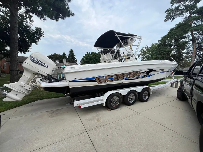 Slide: The Image of 2000 Wellcraft 302 SCARAB SPORT boat on trailer, parked outdoors with trees in background. - 6