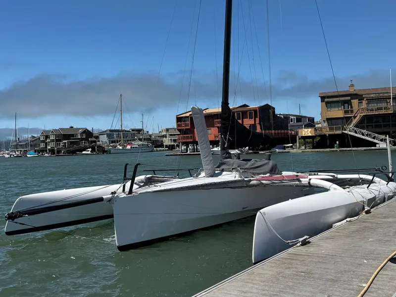 Slide: The Image of 2015 Marstrom Seacart 30 trimaran docked in a marina with waterfront buildings. - 1