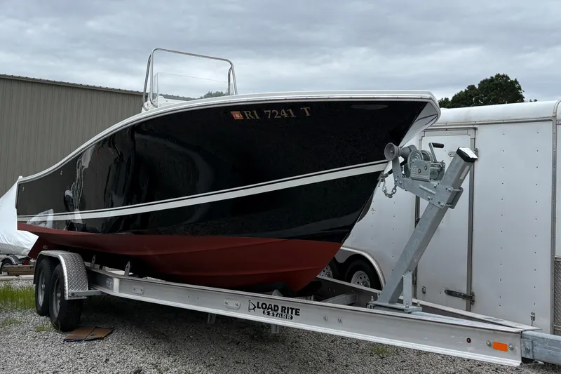 Slide: The Image of 2005 Regulator 24 Classic boat on trailer, black and red hull, parked outdoors. - 2