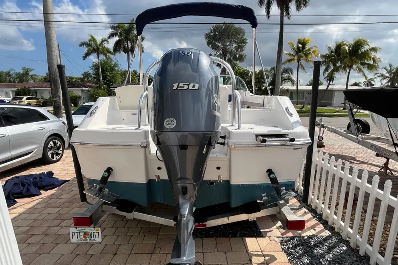 Slide: The Image of 2021 Robalo 207R boat with 150 HP engine, parked on a sunny driveway. - 9
